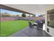 Covered patio featuring comfortable seating with an outdoor grill overlooking the manicured backyard at 7658 W Boca Raton Rd, Peoria, AZ 85381