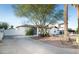 Exterior side view of the home showing rock landscaping, gated driveway, and mature trees at 1512 E Cypress St, Phoenix, AZ 85006