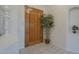 An inviting home entrance featuring a tiled floor, a wood door, and a green leafy plant at 17770 N 66Th Ln, Glendale, AZ 85308