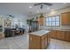 Open concept kitchen with center island, light wood cabinets, and tile flooring adjacent to living room at 17770 N 66Th Ln, Glendale, AZ 85308