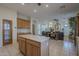 Bright kitchen featuring center island, light wood cabinetry, and tile flooring extending to living area at 17770 N 66Th Ln, Glendale, AZ 85308