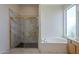 Light-filled main bathroom with a separate shower, a tub, and a large window at 17770 N 66Th Ln, Glendale, AZ 85308