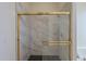 Modern bathroom shower featuring marble tile, black honeycomb floor and gold accents at 17770 N 66Th Ln, Glendale, AZ 85308