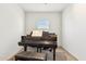A grand piano, a bench, and a window in a small, carpeted room at 18333 N Presley Ln, Maricopa, AZ 85138