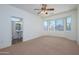 Comfortable bedroom with a large window, neutral carpet and an attached bath with a pedestal sink at 18651 N Salerno Ct, Surprise, AZ 85387