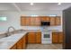 Functional kitchen with wooden cabinets, white appliances, and a stainless steel microwave at 18651 N Salerno Ct, Surprise, AZ 85387