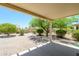 Covered patio offers respite in a desert landscaped backyard featuring gravel, mature trees and foliage at 18651 N Salerno Ct, Surprise, AZ 85387