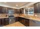 Well-lit kitchen with dark wood cabinets, stainless steel appliances, and stylish tile backsplash at 215 S 132Nd St, Chandler, AZ 85225