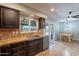 Kitchen featuring dark wood cabinets, stainless steel appliances, tile backsplash, and access to the patio at 215 S 132Nd St, Chandler, AZ 85225