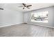 Bright living room showing a large window, gray wood-look tile flooring, and a ceiling fan at 3126 W Stella Ln, Phoenix, AZ 85017