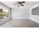 Bright living room with wood-look tile flooring, a ceiling fan, and a large window for natural light at 3126 W Stella Ln, Phoenix, AZ 85017