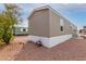 Tan-sided mobile home with white trim and desert landscaping under a partly cloudy sky at 320 E Mckellips Rd # 45, Mesa, AZ 85201