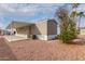 Tan mobile home with an awning-covered porch, desert landscaping, and bright blue sky at 320 E Mckellips Rd # 45, Mesa, AZ 85201