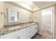 Bathroom with double sinks, granite countertops, and a stylish tiled shower enclosure at 5533 W Sunnyside Dr, Glendale, AZ 85304