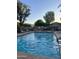 Community pool with mature trees and foliage, metal fencing, and lounge seating at 7052 E Kessler Ave, Mesa, AZ 85209