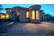 Stunning stone and stucco home with arched windows and desert landscaping illuminated at twilight at 8024 E Lone Mountain Rd, Scottsdale, AZ 85266