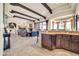 Expansive living room showcasing travertine floors, exposed beams, wet bar, and seamless flow to outdoor spaces at 8024 E Lone Mountain Rd, Scottsdale, AZ 85266