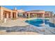 A stunning backyard pool with travertine decking sits in front of a luxury home at 8024 E Lone Mountain Rd, Scottsdale, AZ 85266