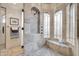 Corner shower with elegant travertine tile, bronze fixtures, arched windows, and a glass door at 8024 E Lone Mountain Rd, Scottsdale, AZ 85266