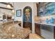 Stylish wet bar with custom cabinets, granite counters, wine fridge, and decorative wrought iron doorway at 8024 E Lone Mountain Rd, Scottsdale, AZ 85266