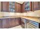 Elegant wet bar with granite countertop, wine fridge, custom cabinetry, and glass-front display cabinets at 8024 E Lone Mountain Rd, Scottsdale, AZ 85266