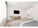Modern bedroom with light wood floors, a wall-mounted TV, and minimal decor exudes a clean, contemporary aesthetic at 10641 E Blue Sky Dr, Scottsdale, AZ 85262