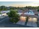 Scenic aerial view of homes with tile roofs, green lawns, and mountain views in the distance at sunset at 11416 N Century Ln, Scottsdale, AZ 85254
