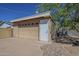 Detached garage with a beige door, side entrance and landscaping around it at 1530 E Loma Ln, Phoenix, AZ 85020