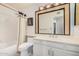 Well-lit bathroom with a shower and tub combination, sink, and an decorative mirror at 1549 N La Rosa Dr, Tempe, AZ 85288