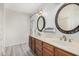 Bathroom with double vanity, wood cabinets, updated light fixtures and decorative mirrors at 1549 N La Rosa Dr, Tempe, AZ 85288