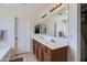 Bright bathroom featuring double sinks, a large mirror and wood cabinets, promoting organized storage at 18182 W Desert Ln, Surprise, AZ 85388