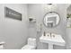 Charming powder room featuring a pedestal sink, round mirror, and modern wall art at 21575 E Twin Acres Ct, Queen Creek, AZ 85142
