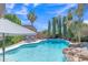 Backyard oasis showcasing beautiful in-ground pool with rock waterfall feature and mature landscaping at 21575 E Twin Acres Ct, Queen Creek, AZ 85142