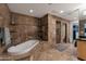 Luxurious bathroom featuring a soaking tub, a separate shower, and stone tile at 22039 N 86Th Ave, Peoria, AZ 85383