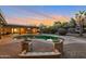 Scenic backyard showcases a pool, lush greenery, comfortable lounge seating, and a colorful sunset, perfect for outdoor living at 22039 N 86Th Ave, Peoria, AZ 85383