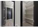 Hallway with pantry featuring multiple shelves for storage and black trim door at 25846 W Denver Hill Dr, Wittmann, AZ 85361