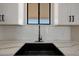 Close-up of a modern kitchen featuring a black sink, white cabinets, and quartz countertops at 25846 W Denver Hill Dr, Wittmann, AZ 85361