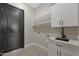 Functional laundry room with white cabinets, sink and open shelving at 25846 W Denver Hill Dr, Wittmann, AZ 85361