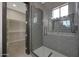 Modern tiled shower with glass enclosure, shelving and door to the walk-in closet at 25846 W Denver Hill Dr, Wittmann, AZ 85361