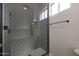 A modern bathroom shower featuring grey tiled walls, a glass door, and black hardware at 25846 W Denver Hill Dr, Wittmann, AZ 85361