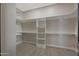 Spacious walk-in closet with custom shelving and ample storage space with wood-look ceramic tile flooring at 25846 W Denver Hill Dr, Wittmann, AZ 85361