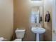 Cozy half bath with a pedestal sink, decorative mirror, and neutral wall color at 2976 E Clifton Ave, Gilbert, AZ 85295