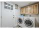 Bright laundry room with Whirlpool washer and dryer, white door and light wood cabinets at 31259 N 42Nd Pl, Cave Creek, AZ 85331