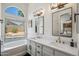 Bright bathroom with a soaking tub under a large window with double sink vanity and modern mirrors at 4440 E Tether Trl, Phoenix, AZ 85050