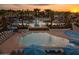 Aerial view of community pool with multiple pools, lounge chairs, umbrellas, and palm trees at 6190 N Sunrise Ln, Buckeye, AZ 85396