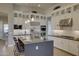 Well-lit kitchen boasts white cabinetry, stainless steel appliances, and a center island with bar stools at 6190 N Sunrise Ln, Buckeye, AZ 85396