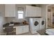 Bright laundry room features a built-in desk, upper cabinets, and modern washer and dryer at 6190 N Sunrise Ln, Buckeye, AZ 85396