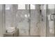 Modern walk-in shower featuring luxurious marble tile, a glass enclosure, and a convenient bench at 6190 N Sunrise Ln, Buckeye, AZ 85396