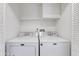 Bright laundry room with white washer and dryer, storage shelf, and neutral walls at 7802 E Rovey Ave, Scottsdale, AZ 85250