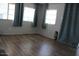 Bright living room featuring modern wood flooring and many windows dressed with teal curtains at 7807 E Main St # D-26, Mesa, AZ 85207